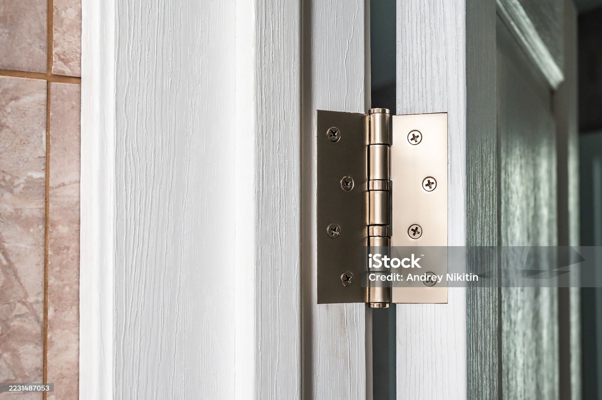 Chrome butt hinge installed on a white door frame